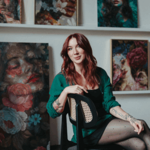 Artist Jess Currier sitting in studio with her oil paintings in the background