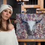 Shana Levenson posing beside a large floral artwork that features chrome balloon text, painted on an Artefex panel.